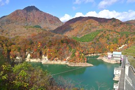 入畑ダム展望台から望む、青い湖と山肌がグラデーション状に紅葉する様子
