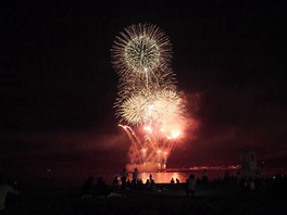 海上から打ちあがる色とりどりの混合花火