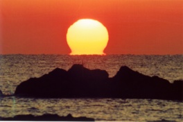 だるま朝日は海面の海水温と大気の温度差により水蒸気に光が屈折して太陽がだるまのように見える現象