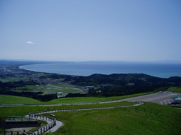 寒風山を覆う青い芝草の向こうに日本海が広がる